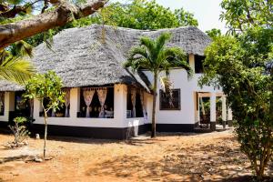 迪亚尼海滩Double room in a villa的白色的房子,拥有茅草屋顶和棕榈树