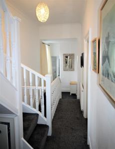 泰恩河畔纽卡斯尔Newcastle - Heaton - Great Customer Feedback - 5 Large Bedrooms - Period Property - Refurbished Throughout的走廊设有白色楼梯和吊灯
