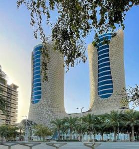 LusailCentury Marina Hotel - Lusail的两座高大的建筑,前面有棕榈树