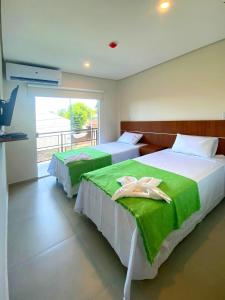 亚松森VIVARIUM APART HOTEL的一间卧室设有两张带绿床单的床和窗户。