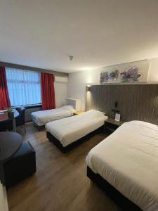 蒂尔堡蒂尔堡城市酒店的酒店客房,设有两张床和一张沙发