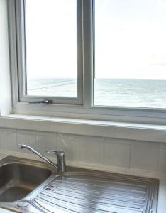 科肯希Fisherman's Cottage的窗户位于厨房水槽上方,享有海景