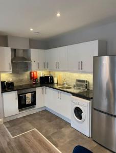 都柏林Central 2-bed Apartment的厨房配有白色橱柜和不锈钢冰箱