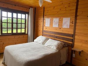 兰舒凯马杜Cabanas Recanto do Rancho - Rancho Queimado的木制客房内的一间卧室,配有一张床