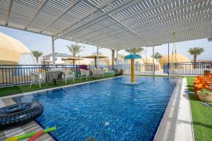 KaliaCamp Sahara的一个带遮阳伞和椅子的游泳池以及一个游泳池