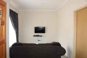 马塞卢ONESI Guest House的客厅配有沙发和墙上的电视