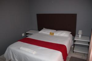 马塞卢ONESI Guest House的一间卧室配有一张带红白毯子的床