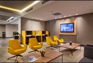 伊斯坦布尔Antasya Residance-Fraser Place的一间设有黄色椅子和桌子的等候室