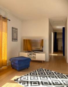 托农莱班Charmant Appartement Pop - Arty的一间带电视和蓝色搁脚凳的客厅