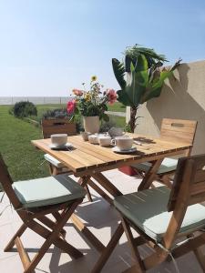 沙特拉永普拉日Studio-terrasse 3* bord de mer Châtelaillon plage的庭院里配有一张带椅子和鲜花的木制野餐桌