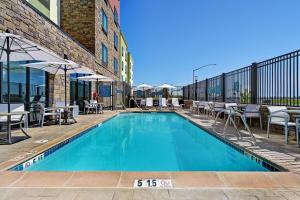 萨克拉门托TownePlace Suites Sacramento Airport Natomas的一座带桌椅的游泳池位于酒店大楼旁