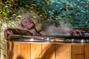 拉罗谢尔Escale Rochelaise B&B, SPA bain nordique et sauna tonneau的一个人躺在浴缸里,蒸汽从浴缸里出来