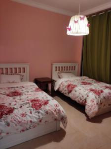 阿吉曼Walk to the Beach, Charming 3-Bedroom Home in Ajman Corniche Residences的一间卧室配有两张床和吊灯。