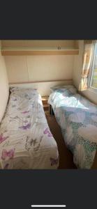 Belton3 bed caravan Norfolk near the coast的小房间设有两张床和窗户