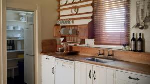北哈夫洛克Rush Cottage的厨房配有白色橱柜、水槽和窗户。