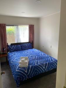 奥克兰The Gardens' Treasure的一间卧室配有蓝色的床和毛巾