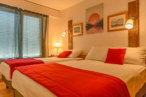 布勒Hotel des Alpes Bulle center的客房内的两张床和红色枕头