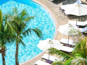 读谷村阿利维亚日光酒店的享有带遮阳伞和棕榈树的游泳池的顶部景致