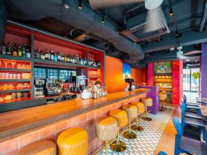 东京COCOSHUKU AKASAKA Premium的一间酒吧,拥有橙色和紫色的墙壁和黄色凳子
