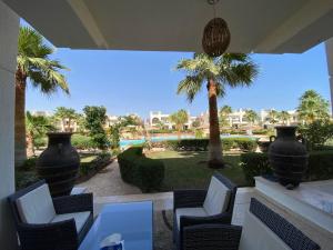 沙姆沙伊赫Renoviertes Luxusapartment Sunny Lakes 1 Sharm El-Sheikh nun auch für Langzeitmieter buchbar的一个带椅子和桌子的庭院,并种植了棕榈树