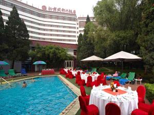 顺义北京国都大饭店的一座带红色桌椅的游泳池以及一座大型建筑