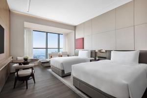 长沙长沙建鸿达JW万豪酒店的酒店客房设有两张床和一张桌子。
