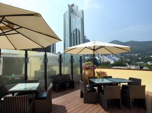 深圳深圳蛇口鸿隆公寓(蛇口海上世界)的阳台上配有两张桌子和椅子及遮阳伞