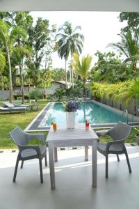 本托塔Eldezo Relax Paradise (Pvt) Ltd的一张白色的桌子和两把椅子以及游泳池