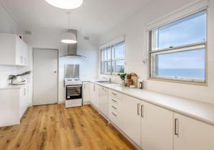 格莱内尔格Glenelg Beach House With Private Beachfront Pool的一间厨房,配有白色的橱柜和大窗户