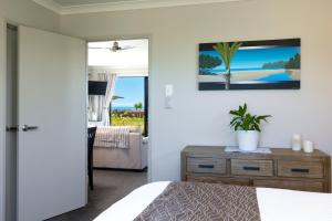 布伦海姆Ocean View Beachfront Apartment的一间卧室配有一张床和一个装有植物的梳妆台