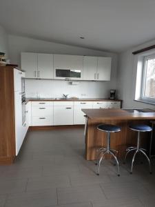 西海姆Apartment im Salzburger Seenland的厨房配有白色橱柜、木桌和凳子