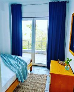 托罗尼Villa Ulyana Toroni - Front seaview, First line, Fireplace的一间卧室配有床和蓝色窗帘的窗户