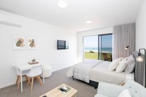 格雷默斯Views over Tasman, New luxury boutique studio overlooking the Tasman Sea的白色卧室配有床和桌椅