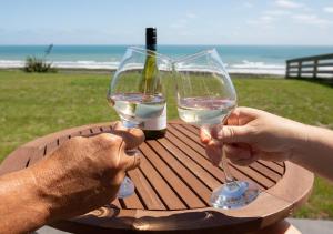 格雷默斯Views over Tasman, New luxury boutique studio overlooking the Tasman Sea的两个人在桌子边拿着白葡萄酒