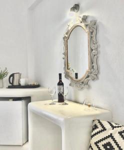 卡马利Villa Maina的一张带镜子的白色桌子和一瓶及眼镜