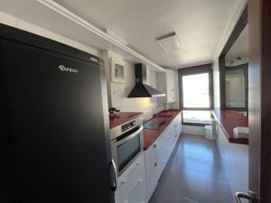 桑托尼亚Duplex Bahía de Santoña的厨房配有白色橱柜和黑色冰箱。