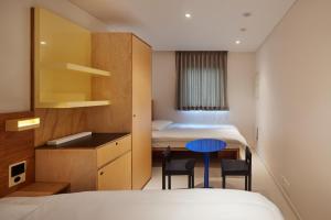 首尔Mangrove Sinseol的酒店客房带两张床和一张桌子以及椅子。