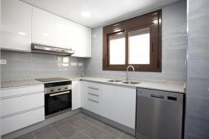 坎布里尔斯Apartamentos Ocea的厨房配有白色橱柜、水槽和窗户。