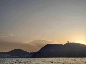 卡沃内拉斯precioso y moderno apartamento frente al mar的日落时分在海山上的十字架