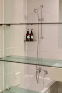 首尔Mangrove Sinseol的浴室设有玻璃淋浴间,架子上装有两瓶酒