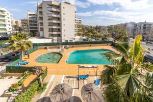 萨洛Apartamentos Alboran-Arysal的享有棕榈树和建筑的游泳池的顶部景致