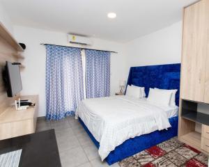 东勒贡OASIS PARK RESIDENCE的一间卧室配有一张带蓝色窗帘的床和电视。