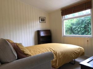 罗伯茨布里奇Adorable Hideaway with log fire and incredible views的一间卧室设有一张床、一个窗口和一把椅子
