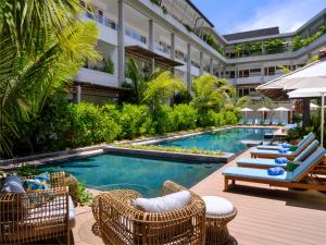 马埃岛laïla, Seychelles, a Marriott Tribute Portfolio Resort的一座带椅子和遮阳伞的游泳池位于一座建筑旁边