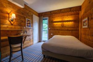 香槟沙隆Cit'Hotel Le Montreal的一间卧室设有木墙、一张床和一张书桌
