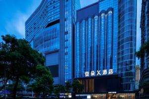 深圳深圳罗湖东门步行街亚朵X酒店的一座高大的玻璃建筑,上面有标志