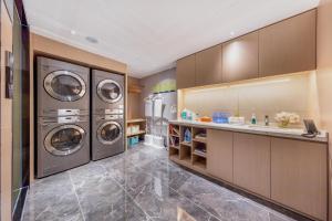 济南济南泉城广场亚朵X酒店的洗衣房配有3台洗衣机和水槽