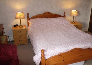 柯比朗斯代尔Ullathorns Farm的一间卧室配有一张木床,桌子上配有两盏灯