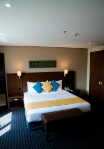 马斯喀特Best Western Premier Muscat的一间卧室配有一张带蓝色和黄色枕头的大床