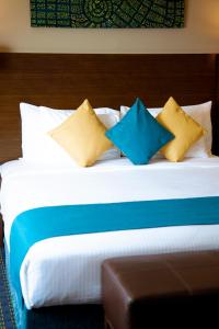 马斯喀特Best Western Premier Muscat的一张带蓝色和黄色枕头的床